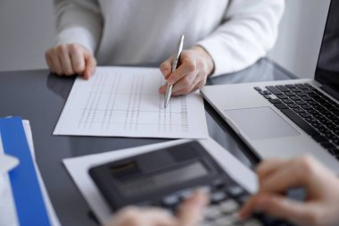 Müşteri için vergi sayarken hesap makinesi ve dizüstü bilgisayar kullanan kadın muhasebeci. İş denetimi kavramları.