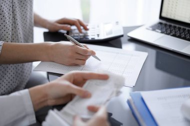 Müşteri ya da iş arkadaşıyla vergi sayarken hesap makinesi ve dizüstü bilgisayar kullanan kadın muhasebeci. İş denetleme ekibi.