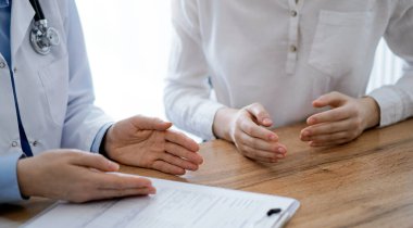 Doktor ve hasta, yukarıdan bakıldığında, klinikteki ahşap masada yan yana otururken bir şeyler tartışıyorlar. Tıp konsepti.