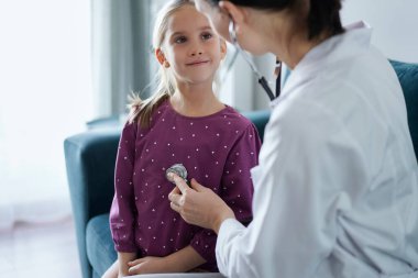 Her zamanki tıbbi muayenede gülümseyen çocuk hasta. Evde doktor ve çocuk hasta var. Tıp, sağlık hizmetleri kavramları.