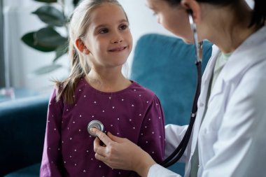 Her zamanki tıbbi muayenede gülümseyen çocuk hasta. Evde doktor ve çocuk hasta var. Tıp, sağlık hizmetleri kavramları.