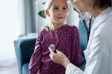 Çocuk hasta her zamanki sağlık kontrolünde. Evde doktor ve çocuk hasta var. Tıp, sağlık hizmetleri kavramları.