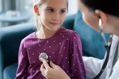 Her zamanki tıbbi muayenede gülümseyen çocuk hasta. Evde doktor ve çocuk hasta var. Tıp, sağlık hizmetleri kavramları.