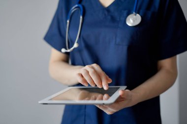 Doktor kadın panorama penceresinin yanında dururken tablet bilgisayar kullanıyor, kapatın. Doktor ya da cerrah iş başında. Tıp konsepti.