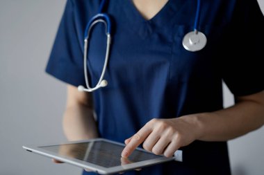 Doktor kadın panorama penceresinin yanında dururken tablet bilgisayar kullanıyor, kapatın. Doktor ya da cerrah iş başında. Tıp konsepti.