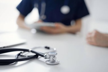 Steteskop arka planda bir doktor ve hastanın önünde tablet bilgisayarın üzerinde duruyordu. Tıp, sağlık hizmeti kavramı.