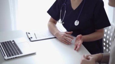 Doktor ve hasta klinikteki yetenek penceresinin yanındaki beyaz masada oturup test sonuçlarını tartışıyor. Tıp konsepti, sağlık hizmetleri.