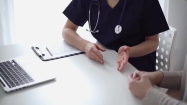 Doktor ve hasta klinikteki yetenek penceresinin yanındaki beyaz masada oturup test sonuçlarını tartışıyor. Tıp konsepti, sağlık hizmetleri.