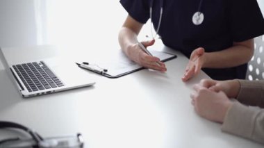 Doktor ve hasta klinikteki yetenek penceresinin yanındaki beyaz masada oturup test sonuçlarını tartışıyor. Tıp konsepti, sağlık hizmetleri.