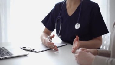 Doktor ve hasta klinikteki yetenek penceresinin yanındaki beyaz masada oturup test sonuçlarını tartışıyor. Tıp konsepti, sağlık hizmetleri.