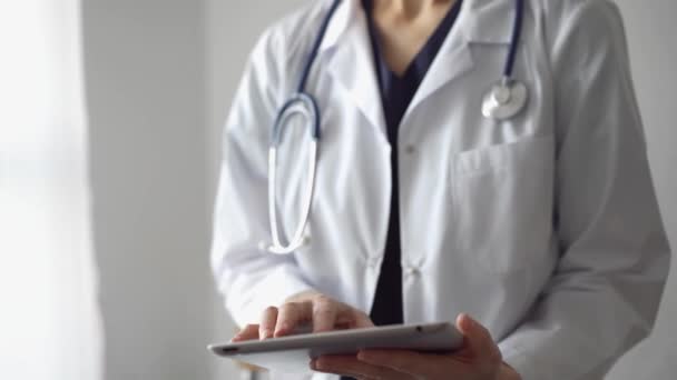 医生工作时使用平板电脑 而站在诊所的全景窗前 医药中的小工具 — 图库视频影像