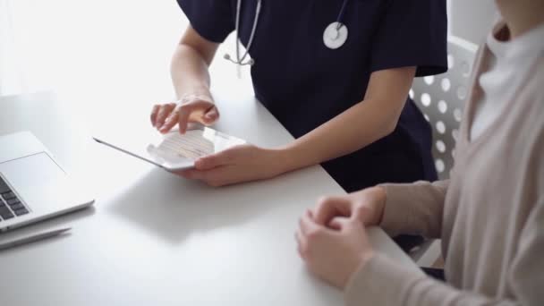진료소의 근처의 책상에 앉아있는 의사와 수없는 의사는 양식을 작성하기 태블릿 — 비디오