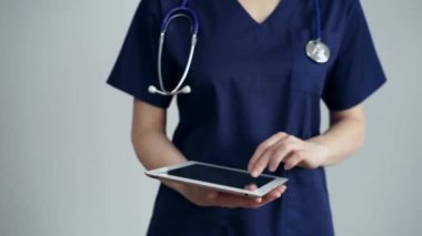 Doktor kadın klinikteki muayenehanede dikilirken tablet bilgisayar kullanıyor, kapat. Doktor ya da cerrah iş başında. Tıp konsepti.