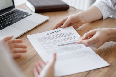 İş kadını avukat, ofisteki ahşap masada meslektaşı ya da müvekkili için bir şey itiraf eden özel sözleşmeye işaret ediyor. İş adamları takım çalışması ve ortaklık, toplantı konsepti.