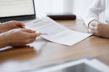 İş kadını avukat, ofisteki ahşap masada meslektaşı ya da müvekkili için bir şey itiraf eden özel sözleşmeye işaret ediyor. İş adamları takım çalışması ve ortaklık, toplantı konsepti.