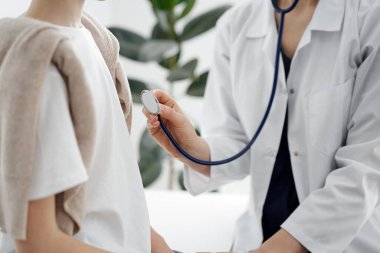 Doktor ve bir çocuk hasta. Doktor steteskop tutuyor ve çocuğu muayene etmeye hazır. Tıpta mükemmel sağlık kavramı.