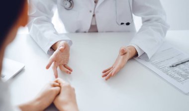 Doktor ve hasta klinikteki masada otururken sağlık sorularını tartışıyorlar. Kapatıyorlar. Tıp ve sağlık hizmetleri kavramı.