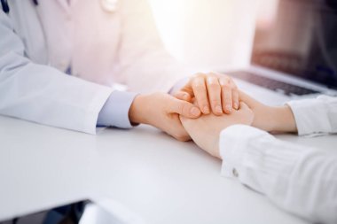 Doktor ve hasta klinikteki masada karşılıklı oturuyorlar. Kadın doktorlara odaklan. Kadına güven veren eller, sadece eller, yakın çekim. Tıp konsepti.