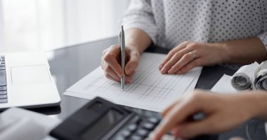 Müşteri için vergi sayarken hesap makinesi ve dizüstü bilgisayar kullanan kadın muhasebeci. İş denetimi ve finans kavramları.