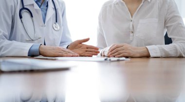 Doktor ve hasta, klinikteki ahşap masada yan yana otururken bir şey tartışıyorlar. Tıp konsepti.