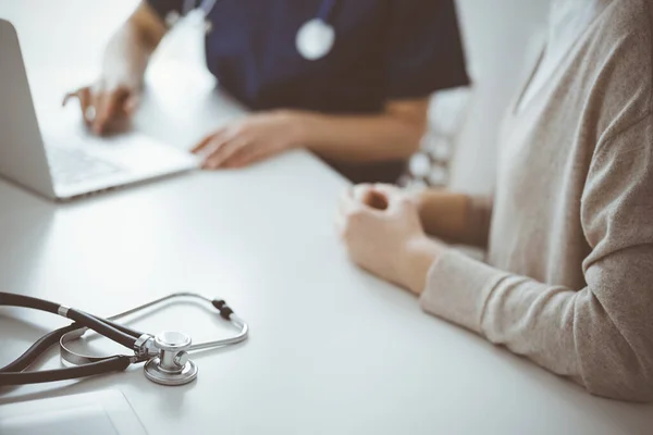 Stetoskop, arka plandaki dizüstü bilgisayarla bir doktor ve hastanın önünde duruyordu. Tıp, sağlık hizmeti kavramı.