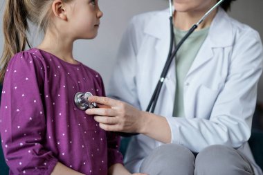 Her zamanki tıbbi muayenede gülümseyen çocuk hasta. Evde doktor ve çocuk hasta var. Tıp, sağlık hizmetleri kavramları.
