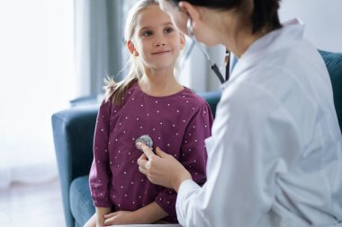 Her zamanki tıbbi muayenede gülümseyen çocuk hasta. Evde doktor ve çocuk hasta var. Tıp, sağlık hizmetleri kavramları.