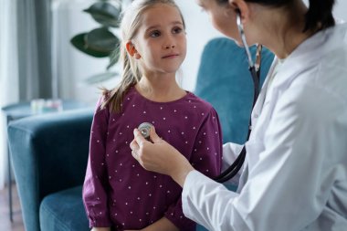 Her zamanki tıbbi muayenede gülümseyen çocuk hasta. Evde doktor ve çocuk hasta var. Tıp, sağlık hizmetleri kavramları.