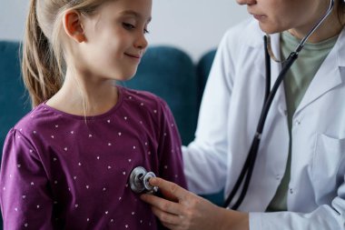 Her zamanki tıbbi muayenede gülümseyen çocuk hasta. Evde doktor ve çocuk hasta var. Tıp, sağlık hizmetleri kavramları.