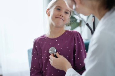 Her zamanki tıbbi muayenede gülümseyen çocuk hasta. Evde doktor ve çocuk hasta var. Tıp, sağlık hizmetleri kavramları.
