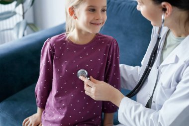 Her zamanki tıbbi muayenede gülümseyen çocuk hasta. Evde doktor ve çocuk hasta var. Tıp, sağlık hizmetleri kavramları.