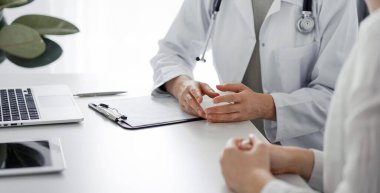 Doktor ve hasta klinikteki masada otururken sağlık muayenesini tartışıyorlar. Mükemmel tıbbi hizmet ve tıp konsepti.