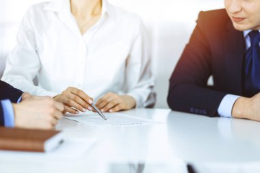 Bir grup iş adamı, erkek ve kadın güneşli bir modern ofiste yapılan bir anlaşmanın detaylarını tartışıyor. Pazarlık ya da iş yerinde tartışırız. Takım çalışması, ortaklık ve iş konsepti.