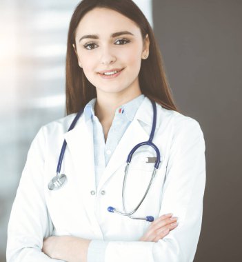 Gülümseyen genç bayan doktor kapalı bir klinikte duruyor..