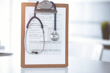 Üzerinde ilaç geçmişi olan steteskop ve dosya güneşli doktorların çalıştığı yerde masada. Tıp konsepti.