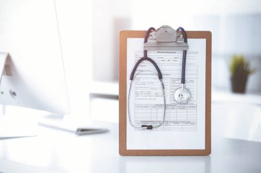 Üzerinde ilaç geçmişi olan steteskop ve dosya güneşli doktorların çalıştığı yerde masada. Tıp konsepti.