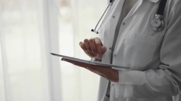 Doktor Kadın Klinikteki Panorama Penceresinin Yanında Dururken Tablet Bilgisayar Kullanıyor — Stok video