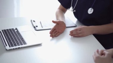 Doktor ve hasta klinikteki yetenek penceresinin yanındaki beyaz masada oturup test sonuçlarını tartışıyor. Tıp konsepti, sağlık hizmetleri.