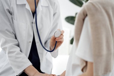 Doktor ve bir çocuk hasta. Doktor steteskop tutuyor ve çocuğu muayene etmeye hazır. Tıpta mükemmel sağlık kavramı.