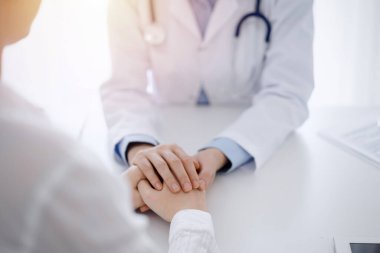 Doktor ve hasta klinikteki masada karşılıklı oturuyorlar. Kadın doktorlara odaklan. Kadına güven veren eller, sadece eller, yakın çekim. Tıp konsepti.