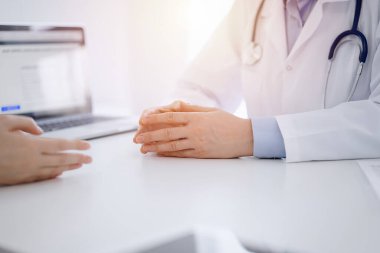 Doktor ve hasta, klinikteki masada karşılıklı otururken mevcut sağlık sorunlarını tartışıyorlar. Sadece ellerinizi yakın plan yapın. Tıp konsepti.