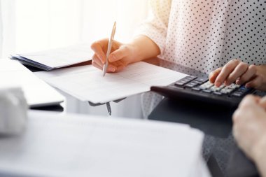 Müşteri için vergi sayarken hesap makinesi ve dizüstü bilgisayar kullanan kadın muhasebeci. İş denetimi ve finans kavramları.