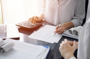 Müşteri için vergi sayarken hesap makinesi ve dizüstü bilgisayar kullanan kadın muhasebeci. İş denetimi ve finans kavramları.