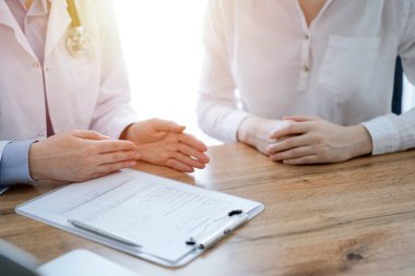 Doktor ve hasta, yukarıdan bakıldığında, klinikteki ahşap masada yan yana otururken bir şeyler tartışıyorlar. Tıp konsepti.