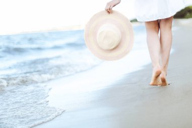 Plajda beyaz şapkalı genç bir kadın. Bacaklarını kapat..