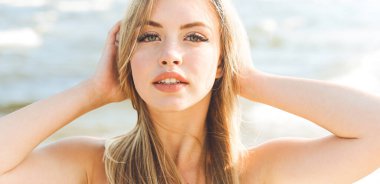 Mutlu sarışın kadın okyanus sahilinde mutlu mesut durup poz veriyor..