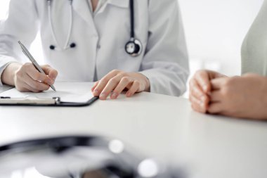 Doktor ve hasta klinikteki masada otururken sağlık muayenesini tartışıyorlar. Tıp konsepti.