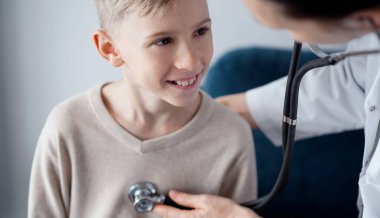 Doktor ve mutlu gülümseyen çocuk hasta ev sağlık kontrolünde. Tıp, sağlık hizmetleri kavramları.