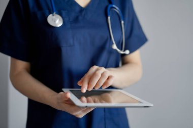 Doktor kadın panorama penceresinin yanında dururken tablet bilgisayar kullanıyor, kapatın. Doktor ya da cerrah iş başında. Tıp konsepti.