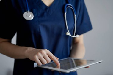 Doktor kadın panorama penceresinin yanında dururken tablet bilgisayar kullanıyor, kapatın. Doktor ya da cerrah iş başında. Tıp konsepti.